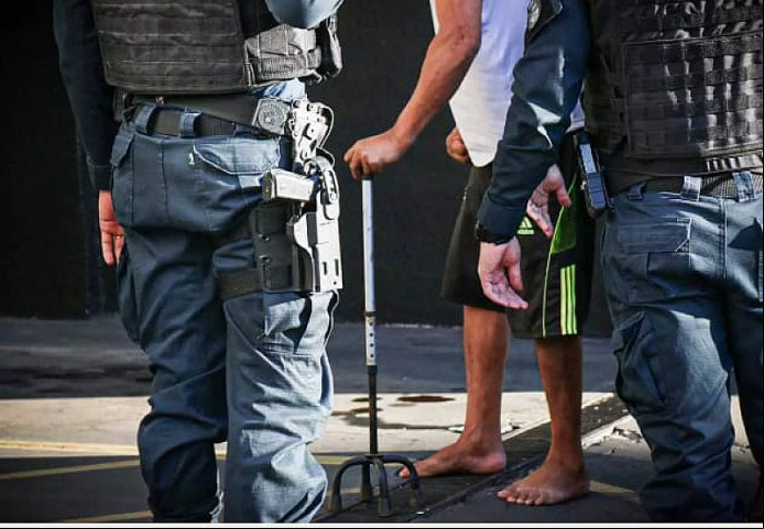 Homem de bengala chegou escoltado na 1ª DP. Imagem: (Henrique Kawaminami)